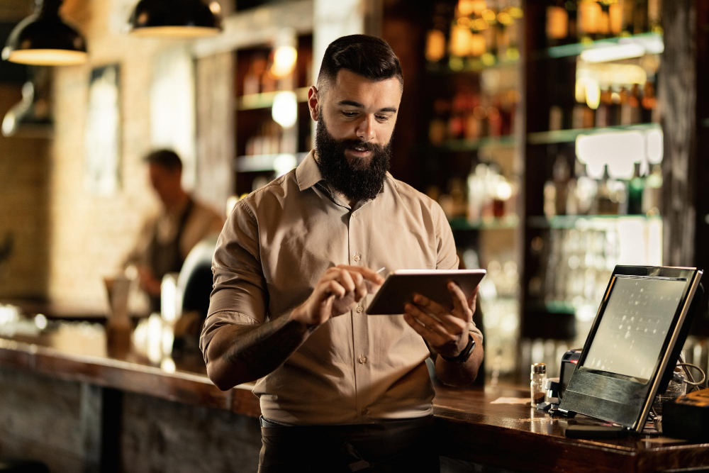 Franchise restaurant manager reviewing location sales on a tablet at the counter
